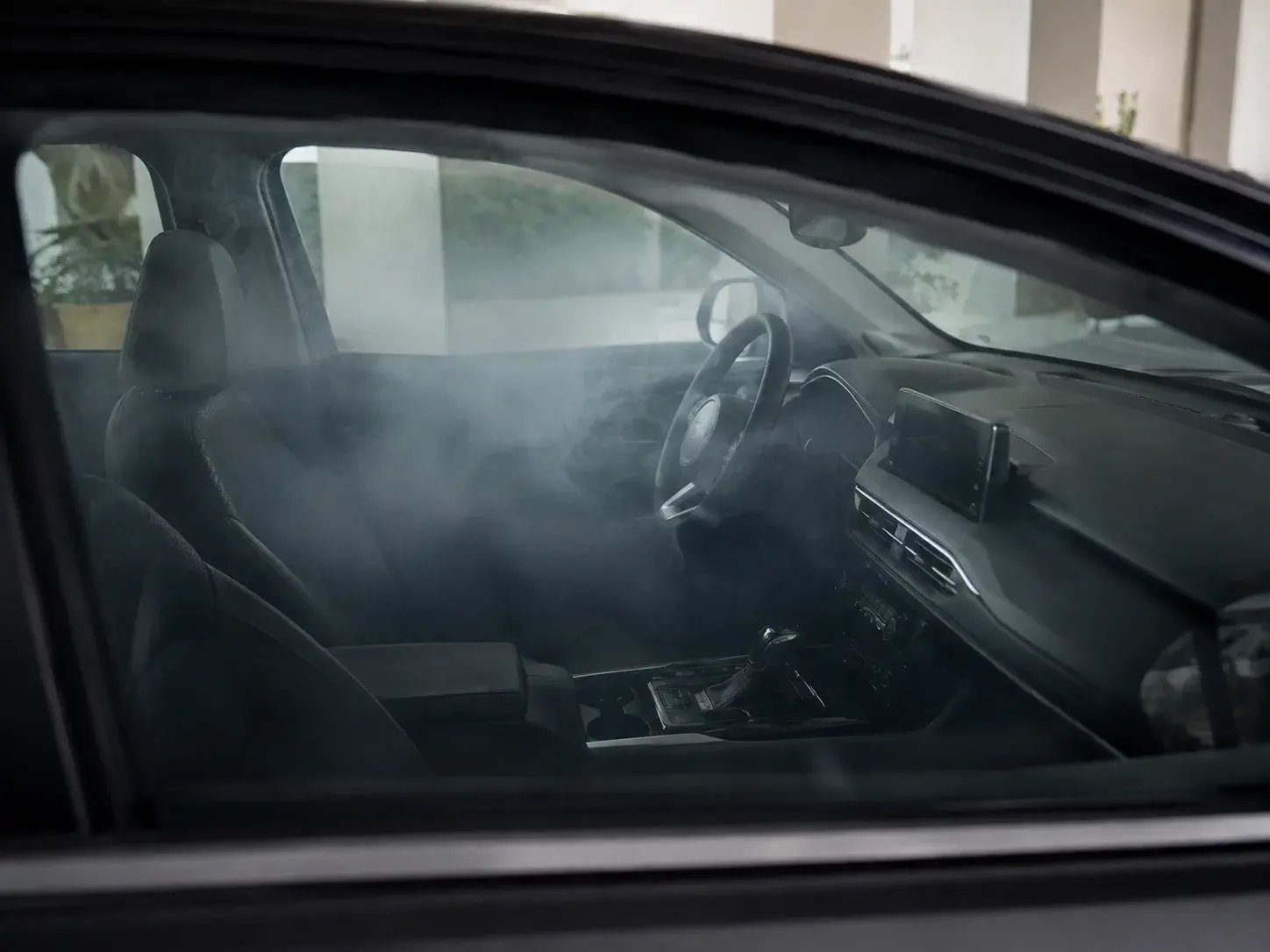 Car cabin during mist treatment, viewed through the open side window