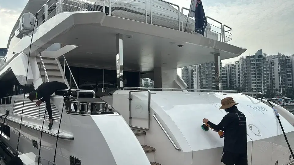 Worker polishing a yacht stern, wide deck view