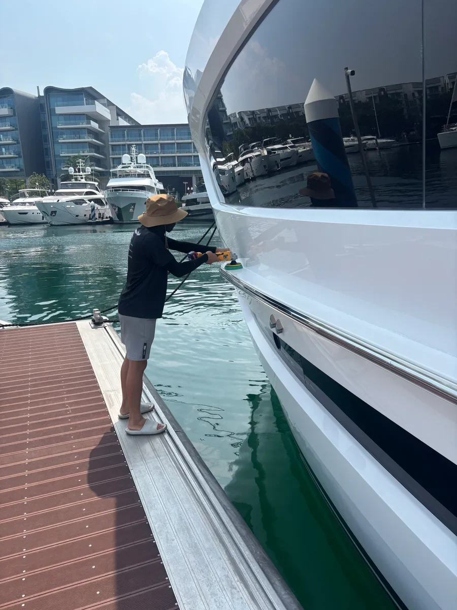 Worker polishing the side of a yacht